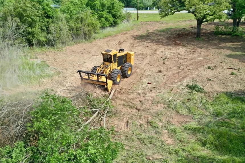 A bulldozer clearing brush and trees from a plot of land