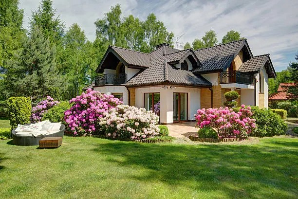 A house with a pristine lawn and flowering bushes